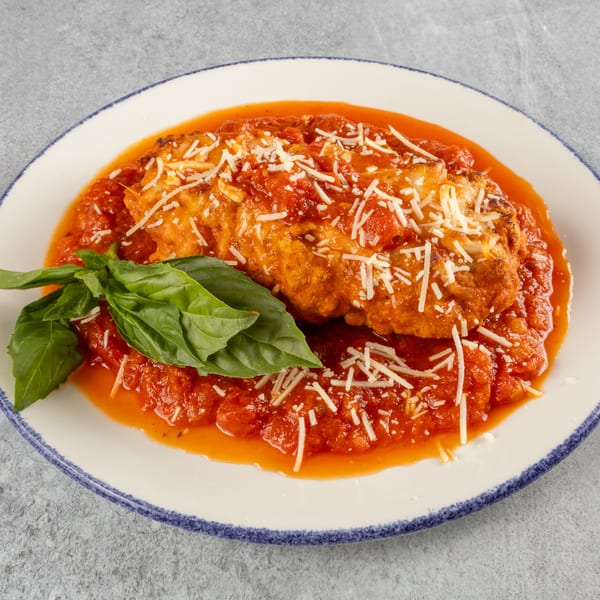 Chicken parmesan with marinara sauce, shredded cheese, and fresh basil on a white plate.