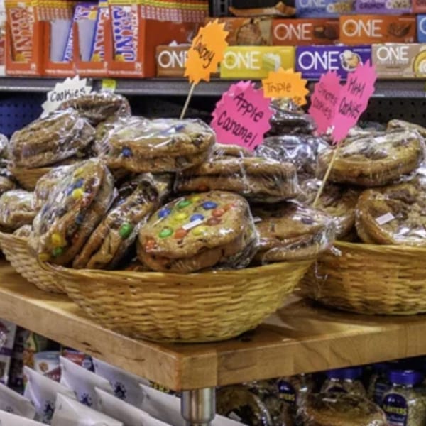 Wicker baskets filled with individually wrapped cookies in various flavors, displayed on a wooden table.